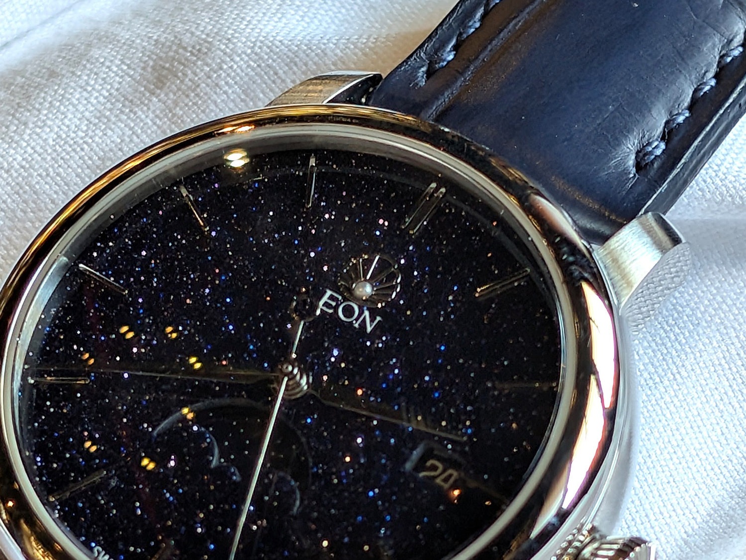 Zoomed in shot of the EON Constellation watch, showing the real pearl in the logo.